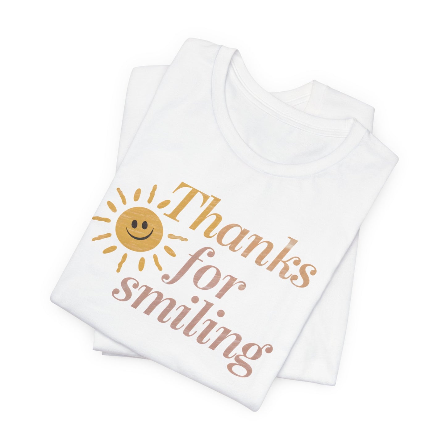 A folded unisex t-shirt with a smiling sun and the slogan Thanks For Smiling with good vibes