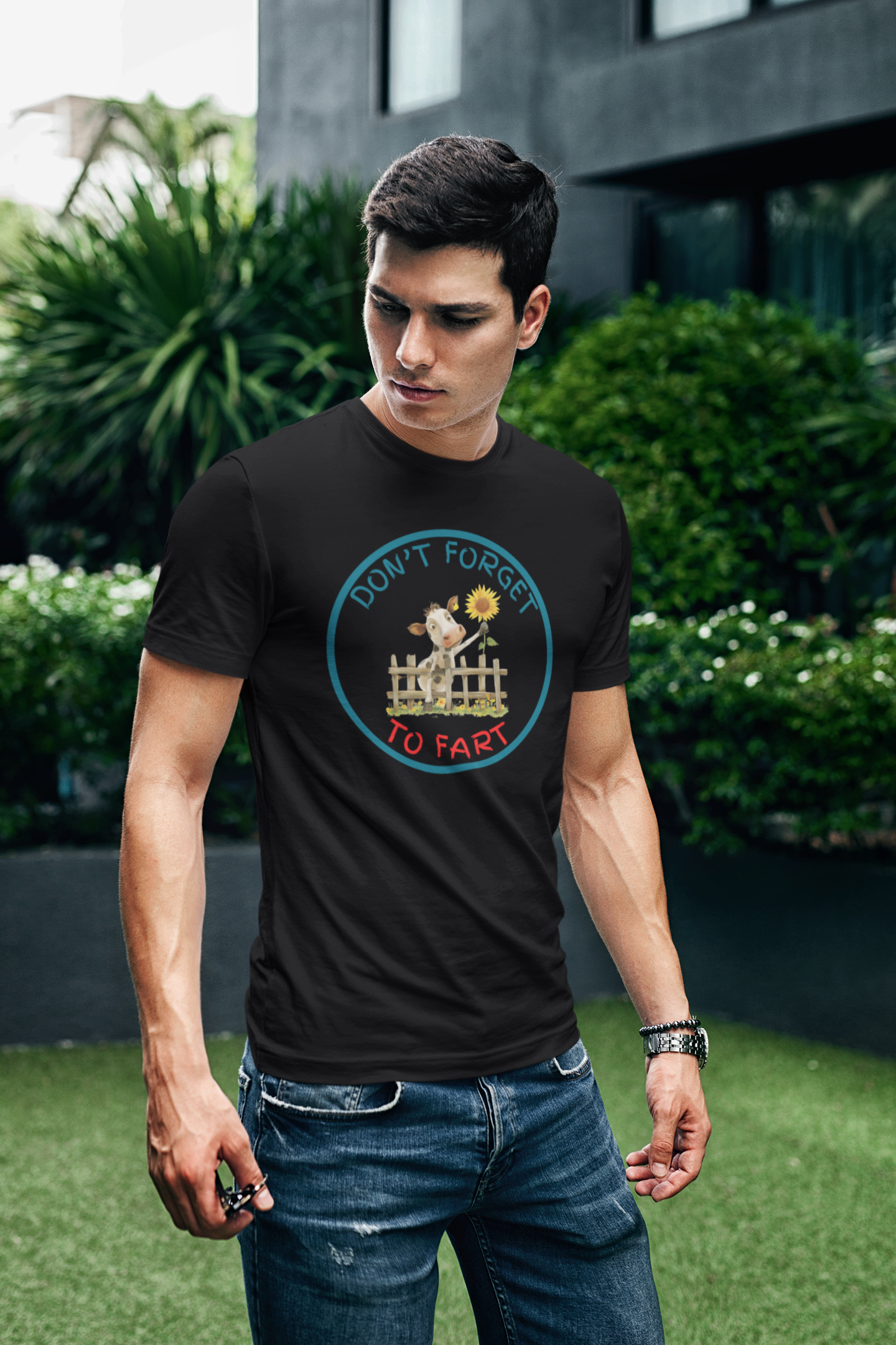 a young man wearing a t shirt of a cow leaning over a fence holding a flower with the funny caption Don't Forget To Fart