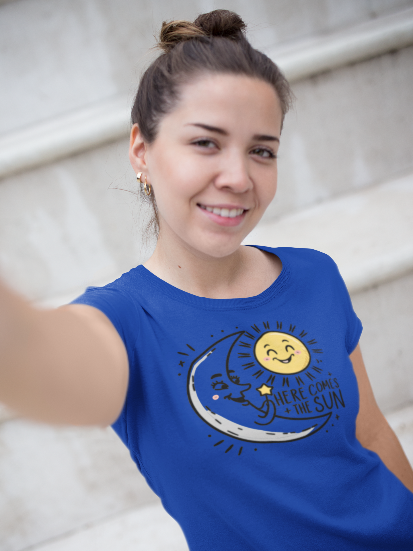 A happy woman taking a selfie wearing a blue a shirt with the caption Here Comes The Sun as the moon greets the rising sun