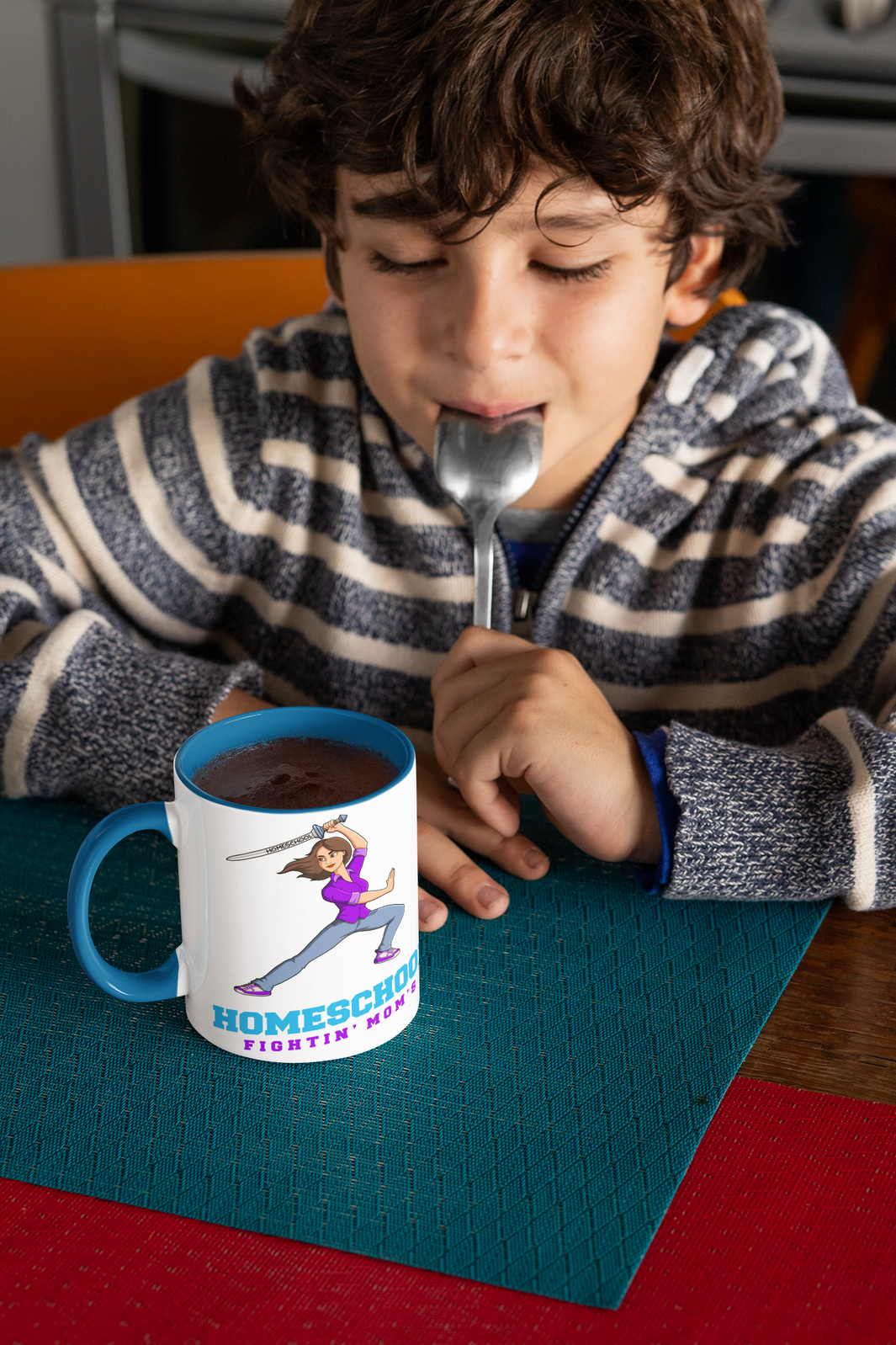 a boy enjoys a cup of hot cocoa. On the cup the words Homeschool Fightin' Mom's the w