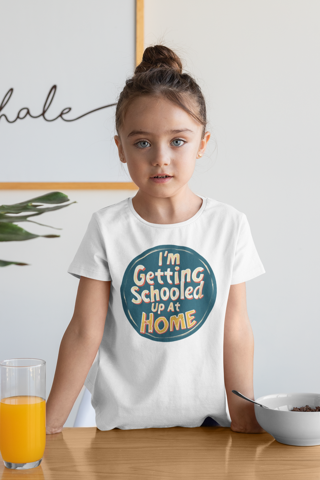 a girl eating breakfast with orange juice wearing a shirt with the caption I'm Getting Schooled Up At Home