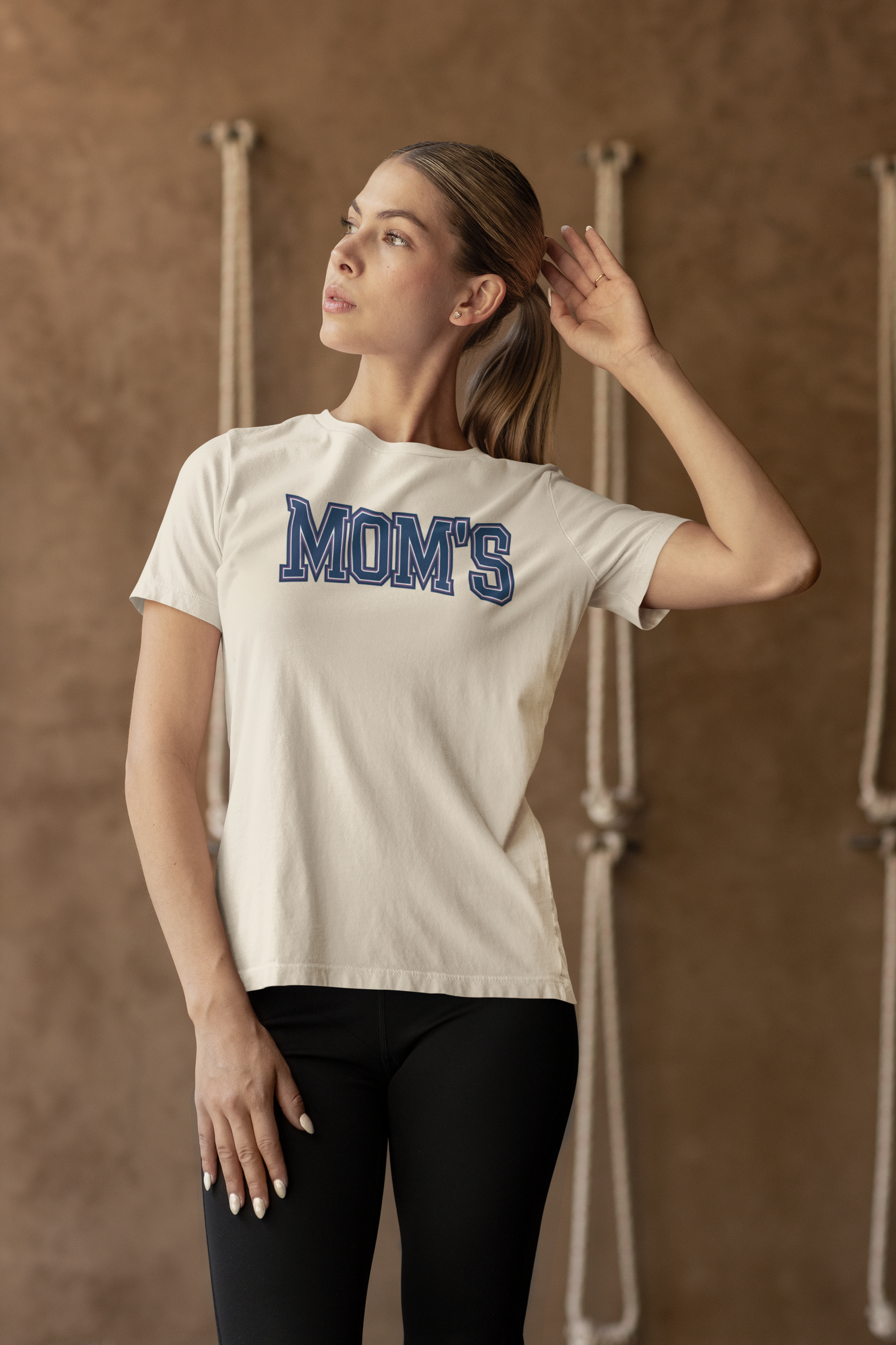a modern woman wearing t shirt with a collegiate style logo with the caption Mom's