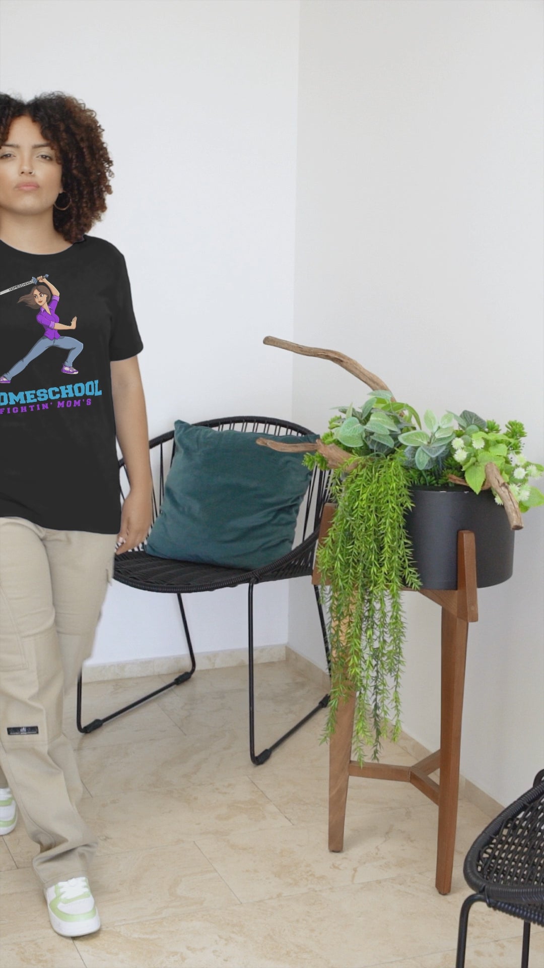 a woman in wearing a t shirt with a illustration of mom branding a sword with the slogan Homeschool Fightin' Mom'