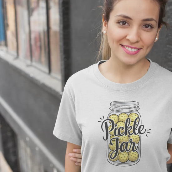 a video of a girl wearing a t-shirt with a mason jar full of pickleballs with the slogan pickle jar