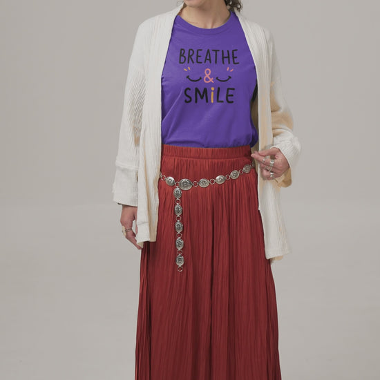 a video with a young woman wearing a t shirt with a happy face and the slogan Breathe & Smile