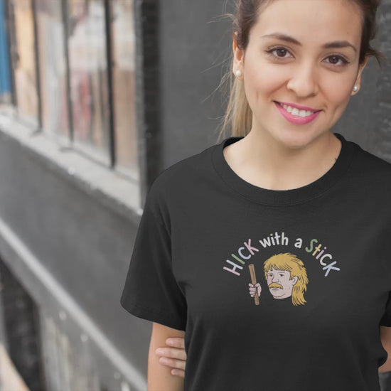 a young woman wearing a shirt with the  illustration of hillbilly with mullet holding a stick with the funny caption Hick with a Stick