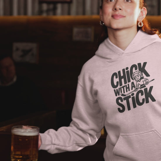 A video of woman sporting a hoodies with the hockey slogan Chick With A Stick