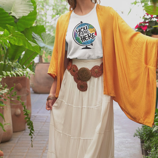 a video with a woman wearing a t-shirt with a illustration of a world globe with the funny caption You Are Here
