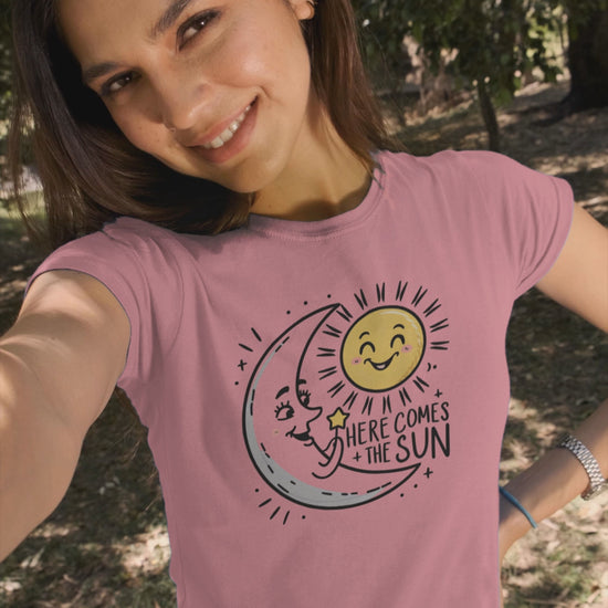 a video with a young woman wearing a t shirt of the moon greeting  the smiling sun with the caption Here Come The Sun