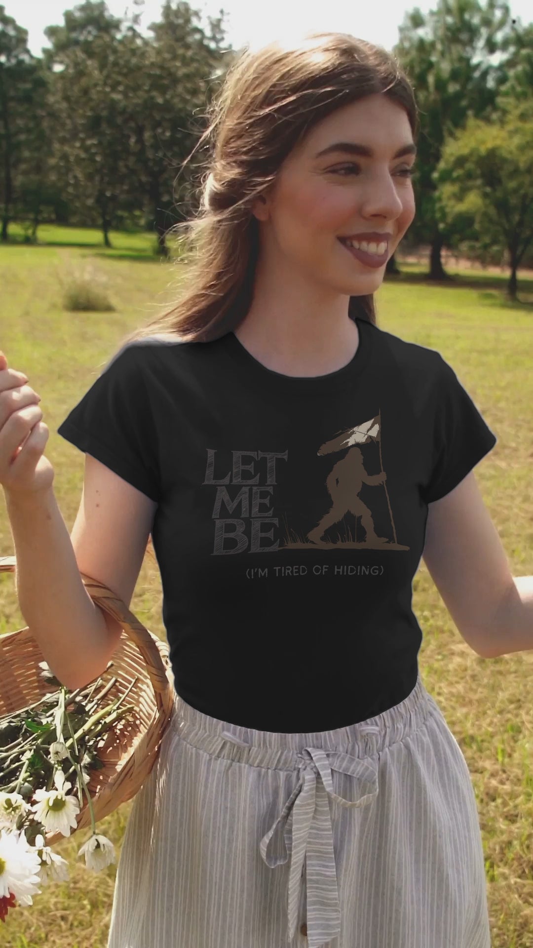 a young woman in video wearing a  t-shirt of bigfoot holding a surronder flag with the caption Let Me Be I'm Tired Of Hiding