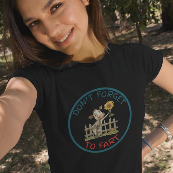 a video of woman wearing a t shirt of a cow leaning over a fence holding a flower with the funny caption Don't Forget To Fart