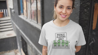 a video with a woman sporting a t shirt with pickles lined up playing pickleball with the slogan Pickle Players Only