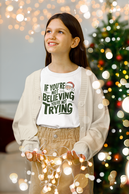 girl in christmas t-shirt wearing a If you're not beieving you're not trying gift 