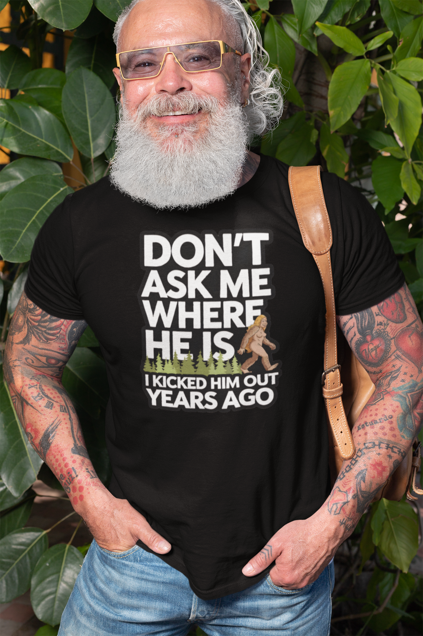 A mature man wearing a T-shirt with a female bigfoot with the caption Don't Ask Me Where He Is I Kicked Him Out Years Ago. Funny Bigfoot shirt