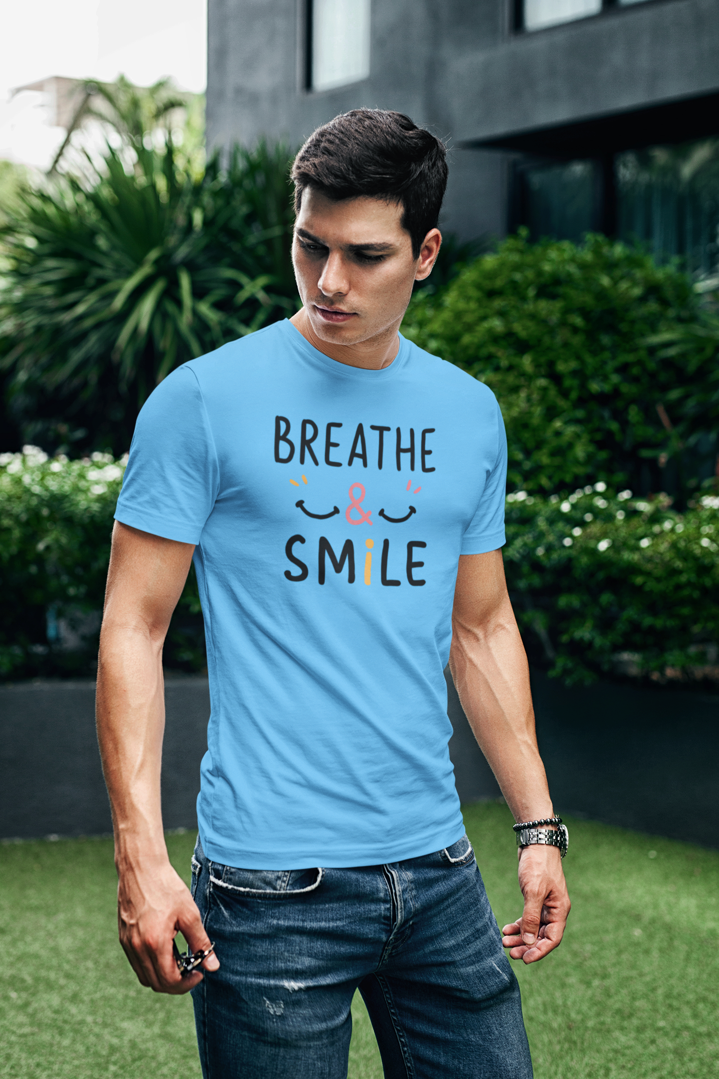 a young man wearing a t shirt with a happy face and the slogan Breathe & Smile