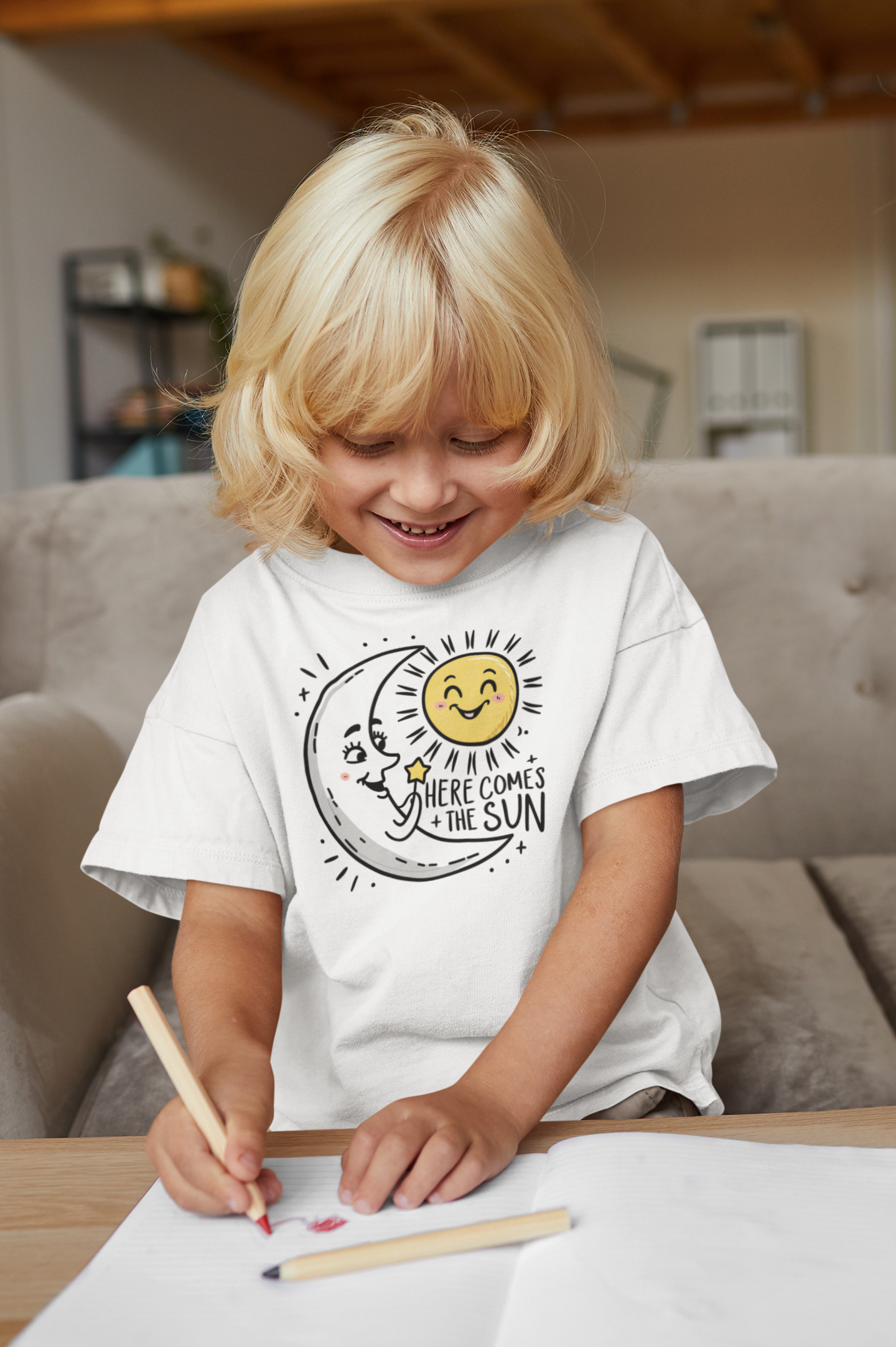 A youth shirt with the happy moon greeting the sun and the slogan here comes the sun